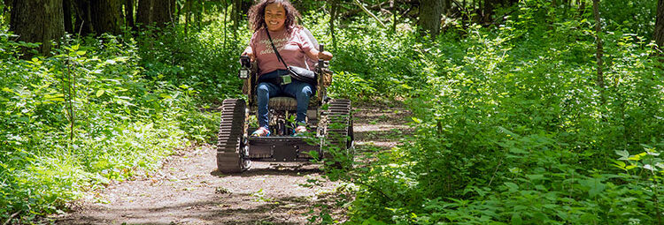 Person in an ATV wheelchair on a dirt path in a state park